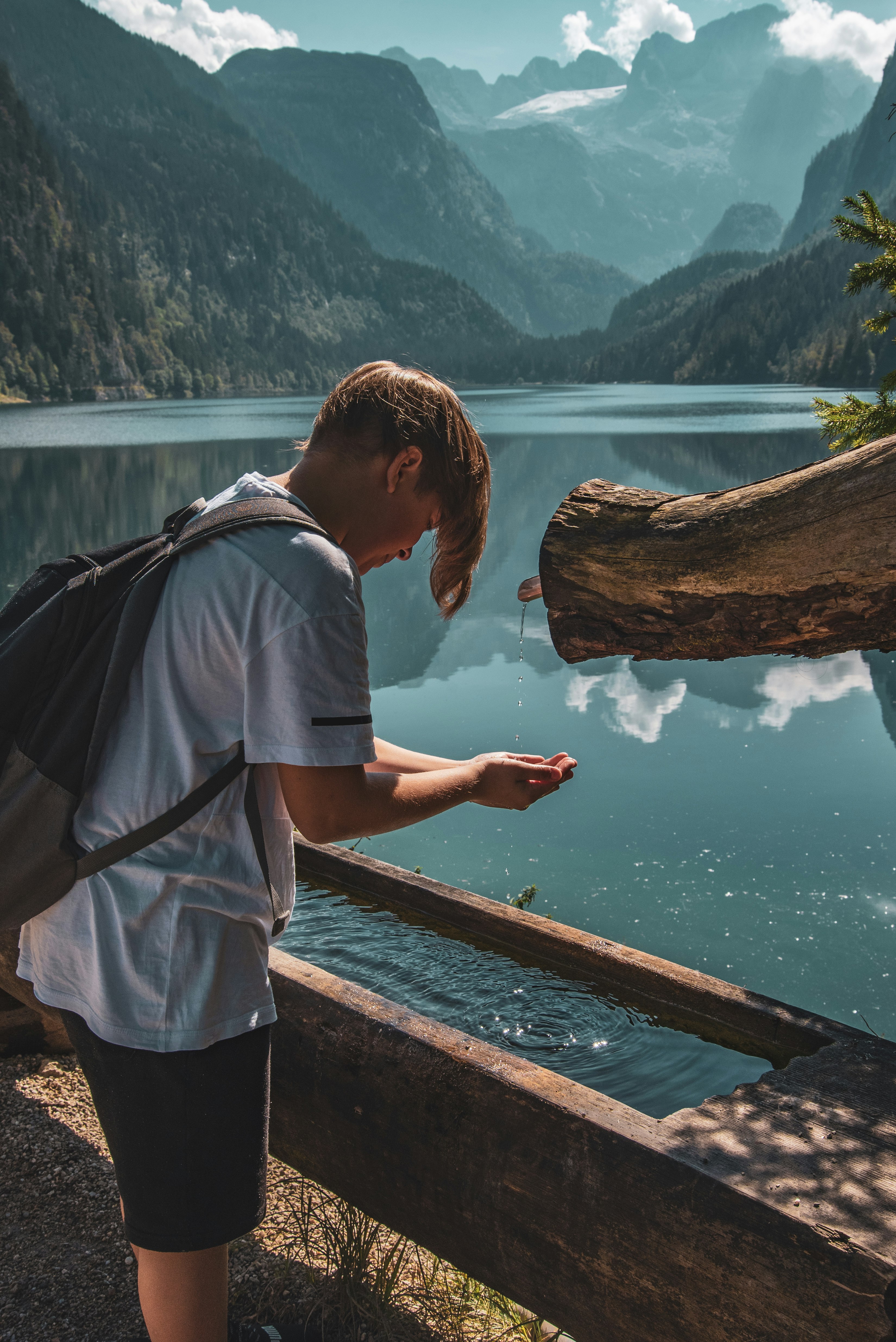 man in blue t-shirt and black backpack standing on dock during daytime